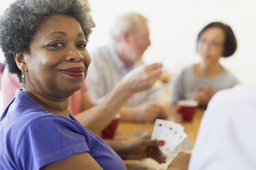 Porträt einer selbstbewussten älteren Frau, die mit Freunden im Gemeindezentrum Karten spielt - CAIF21666