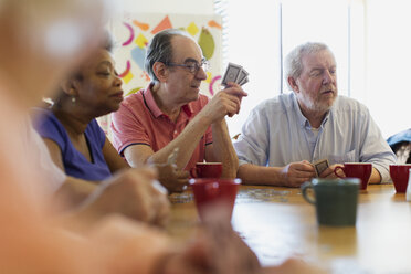 Ältere Freunde spielen Karten am Tisch im Gemeindezentrum - CAIF21667