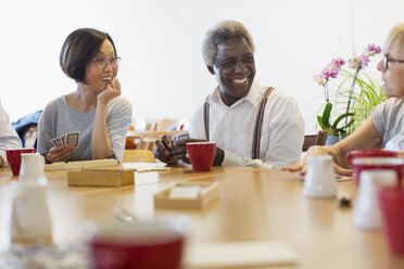 Senior friends playing games at table in community center - CAIF21681