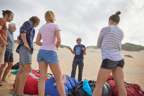 Männlicher Paragliding-Lehrer im Gespräch mit Schülern am Strand, lizenzfreies Stockfoto