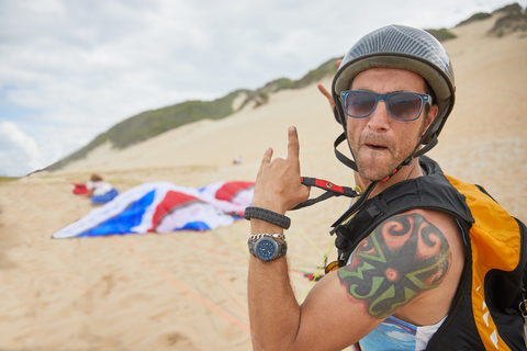 Porträt selbstbewusster, unbekümmerter männlicher Gleitschirmflieger am Strand, lizenzfreies Stockfoto