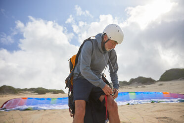 Männlicher Gleitschirmflieger bei der Vorbereitung am sonnigen Strand - CAIF21719