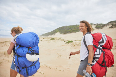 Portrait happy male paraglider with parachute backpack on beach - CAIF21720