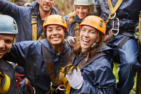 Porträt glückliche, schlammige Freunde beim Seilrutschen, lizenzfreies Stockfoto