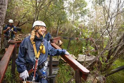 Lächelnde Frau bereitet sich auf eine Seilrutsche im Wald vor - CAIF21739