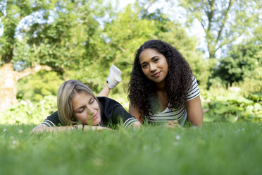 Zwei Freundinnen entspannen im Gras in einem Park - HHLMF00354