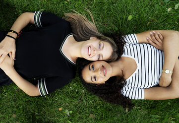 Two girlfriends relaxing in a park, lying on grass - HHLMF00356