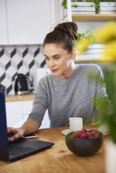 Junge Frau, die von zu Hause aus arbeitet und einen Laptop benutzt - ABIF00914