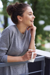 Junge Frau trinkt Morgenkaffee auf dem Balkon - ABIF00921
