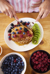 Frau isst Pfannkuchen mit Beeren zum Frühstück - ABIF00932