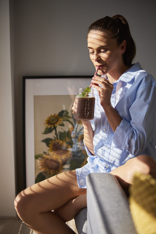 Junge Frau trinkt Smoothie zu Hause, lizenzfreies Stockfoto