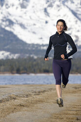 Frau läuft bei winterlichen Bedingungen am Strand von Lake Tahoe, Kalifornien. - AURF01537