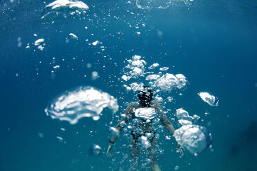 Unterwasseransicht eines Schwimmers hinter einer Wand aus Luftblasen in den tropischen Gewässern vor der Insel Mana, Fidschi. - AURF01592