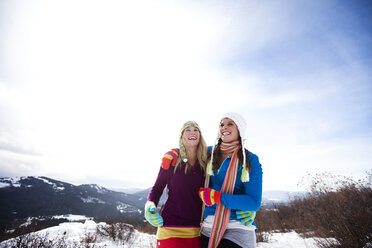 Zwei junge Frauen lachen und lächeln beim Wandern im Schnee an einem schönen Wintertag in Idaho. - AURF01600