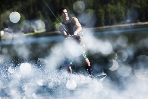 Ein fröhlicher, sportlicher Mann fährt an einem sonnigen Tag in Sandpoint, Idaho, Wakeboard. - AURF01607