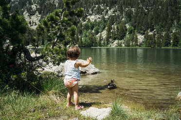 Spanien, Kleines Mädchen steht am Bergsee und winkt einer Ente zu - GEMF02351