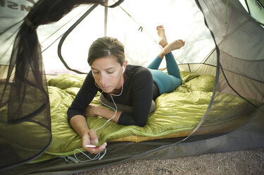 Eine Frau hört ihren iPod und entspannt sich beim Campen im Lost Dutchman State Park in der Nähe von Phoenix, Arizona, November 2011. - AURF01638