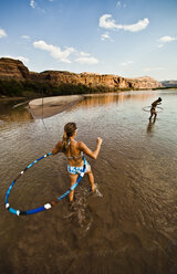 Zwei Frauen, die in einem seichten Fluss spielen und Hula-Hoop tanzen. - AURF01668