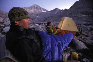 Zwei Männer in Schlafsäcken vor einem Zelt in den Bergen der östlichen Sierra Nevada, Kalifornien. - AURF01671