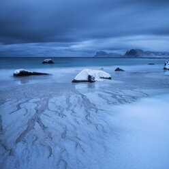 Waves wash over snow covered sand in winter at Myrland beach, Flakstad├©y, Lofoten Islands, Norway - AURF01686