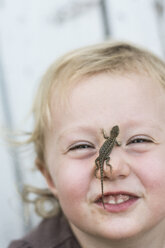 Toddler girl smiles at camera with Sagebrush lizard on nose in Chico, California. - AURF01772
