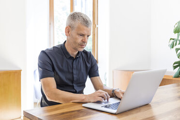 Älterer Mann mit Laptop auf Holztisch - TCF05687