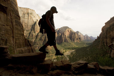 A teenage boy walks down a shady cliff. - AURF01830
