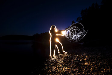 Eine Frau schickt bei Sonnenuntergang in Idaho Energie durch ihren Körper und aus ihren Händen. Dieses Lightpainting-Bild wurde mit einer Langzeitbelichtung und Blitzlicht erstellt. - AURF01847