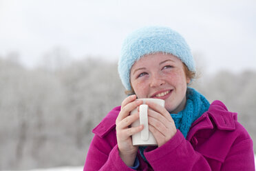 Teenager-Mädchen genießt eine heiße Schokolade draußen im Schnee im Winter, UK. - AURF01883