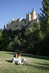 Spanien, Kastilien und Leon, Segovia, Mutter und Tochter sitzen im Gras in der Nähe des Alcazar von Segovia - JSMF00425