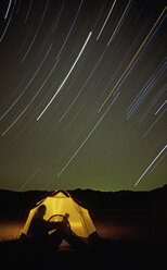 A camper enjoys a calm starry night reading. - AURF01923