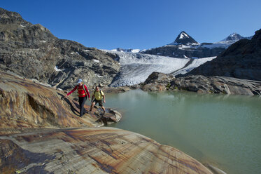 A couple walks past a glacial tarn. - AURF01943