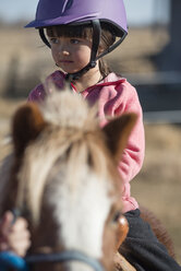 Ein 6-jähriges Cowgirl reitet auf einem kleinen Pony, das genau ihre Größe hat. - AURF01947