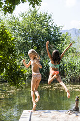 Zwei unbekümmerte Mädchen springen in den Teich - TCF05719