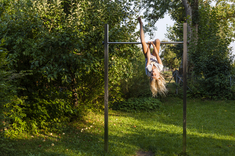 Mädchen, das im Garten an einer Gymnastikstange übt, lizenzfreies Stockfoto