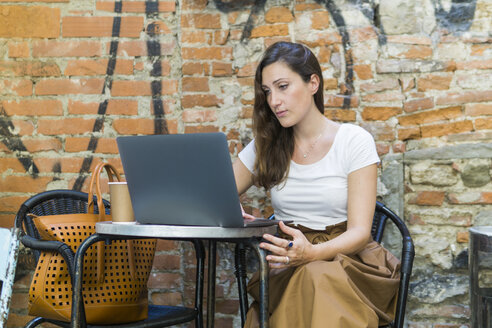Woman using laptop at an outdoor cafe - FBAF00003