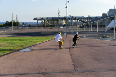 Zwei junge Männer fahren mit Skateboards eine Gasse hinunter - AFVF01480
