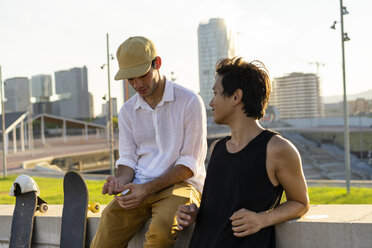 Zwei junge Männer ruhen sich neben Skateboards an einer Wand aus - AFVF01489