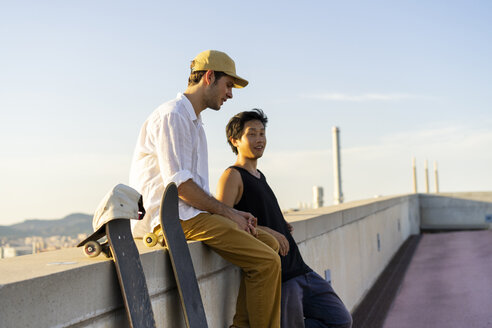 Zwei junge Männer ruhen sich neben Skateboards an einer Wand aus - AFVF01490