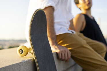 Nahaufnahme von zwei jungen Männern mit Skateboards, die auf einer Mauer sitzen - AFVF01491