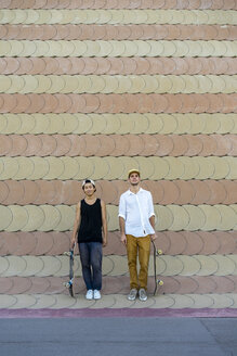 Zwei lächelnde junge Männer mit Skateboards stehen an einer Wand - AFVF01494