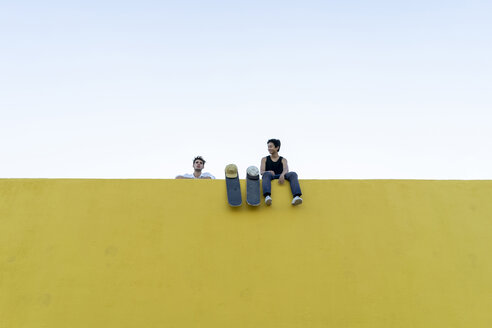 Zwei junge Männer mit Skateboards an einer hohen gelben Wand - AFVF01500