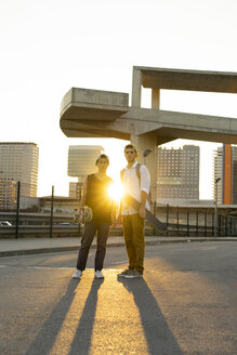 Porträt von zwei jungen Männern mit Skateboards in der Stadt bei Sonnenuntergang - AFVF01502