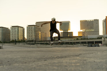 Young man doing a skateboard trick in the city at sunset - AFVF01503