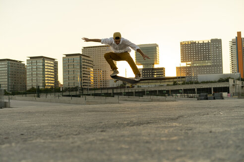 Junger Mann macht einen Skateboardtrick in der Stadt bei Sonnenuntergang - AFVF01504