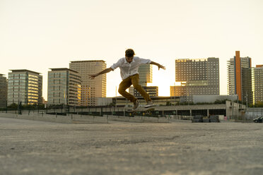 Junger Mann macht einen Skateboardtrick in der Stadt bei Sonnenuntergang - AFVF01505
