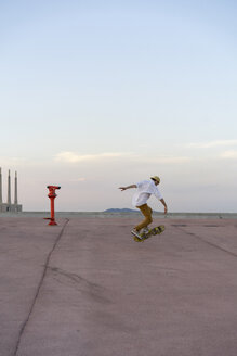 Junger Mann macht einen Skateboardtrick auf einer Fahrbahn in der Abenddämmerung - AFVF01507