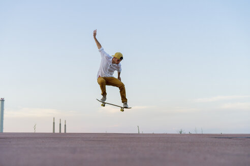 Junger Mann macht einen Skateboardtrick auf einer Fahrbahn in der Abenddämmerung - AFVF01511