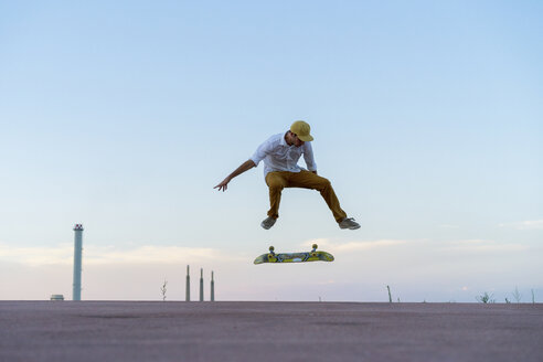 Junger Mann macht einen Skateboardtrick auf einer Fahrbahn in der Abenddämmerung - AFVF01512