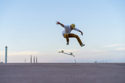 Young man doing a skateboard trick on a lane at dusk stock photo
